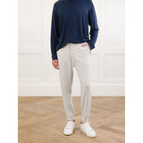 Person wearing a navy long-sleeve shirt, beige pants, and white sneakers in a minimalistic setting.