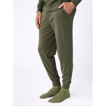 Person wearing olive green jogger pants and socks on a white background
