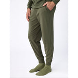 Person wearing olive green jogger pants and socks on a white background