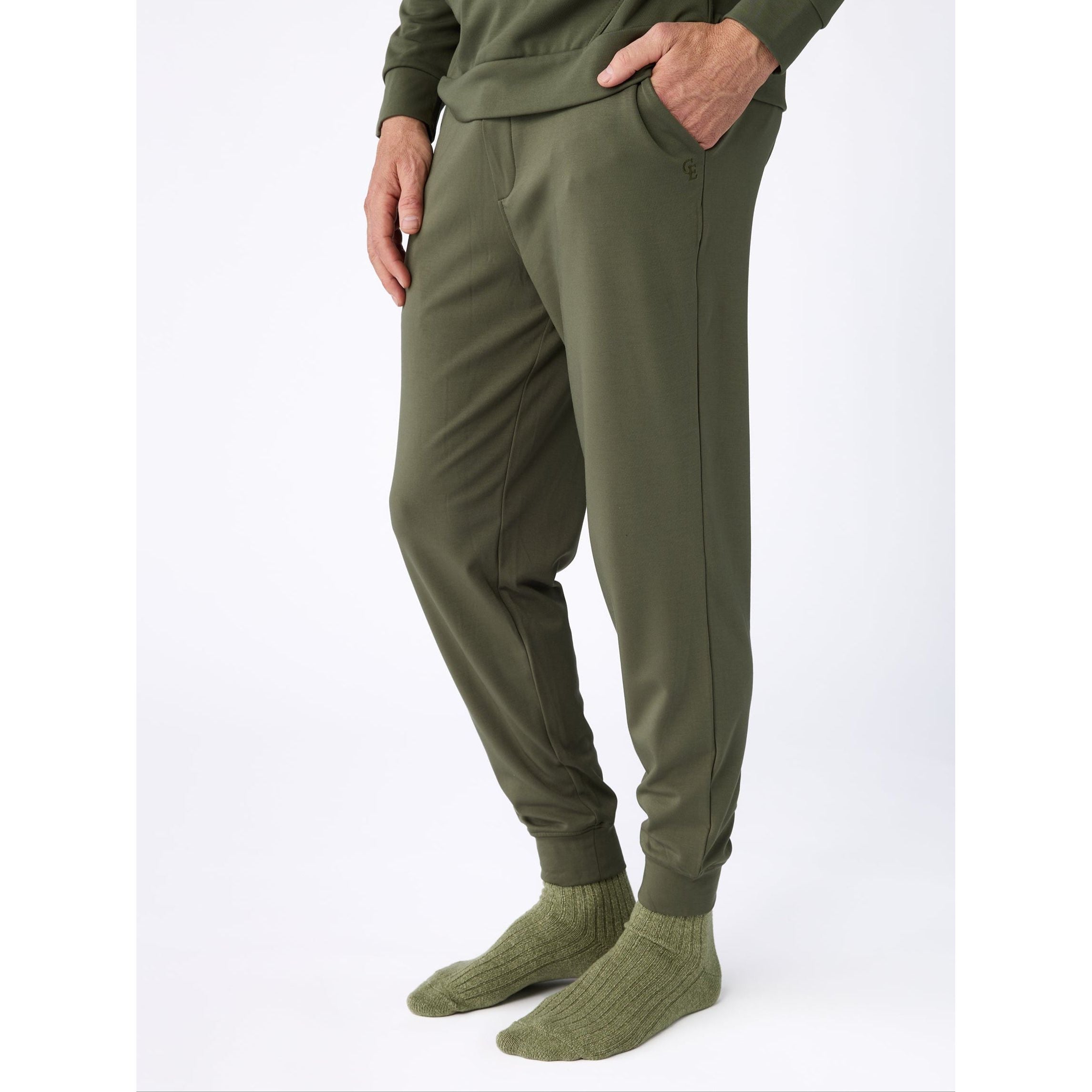 Person wearing olive green jogger pants and socks on a white background