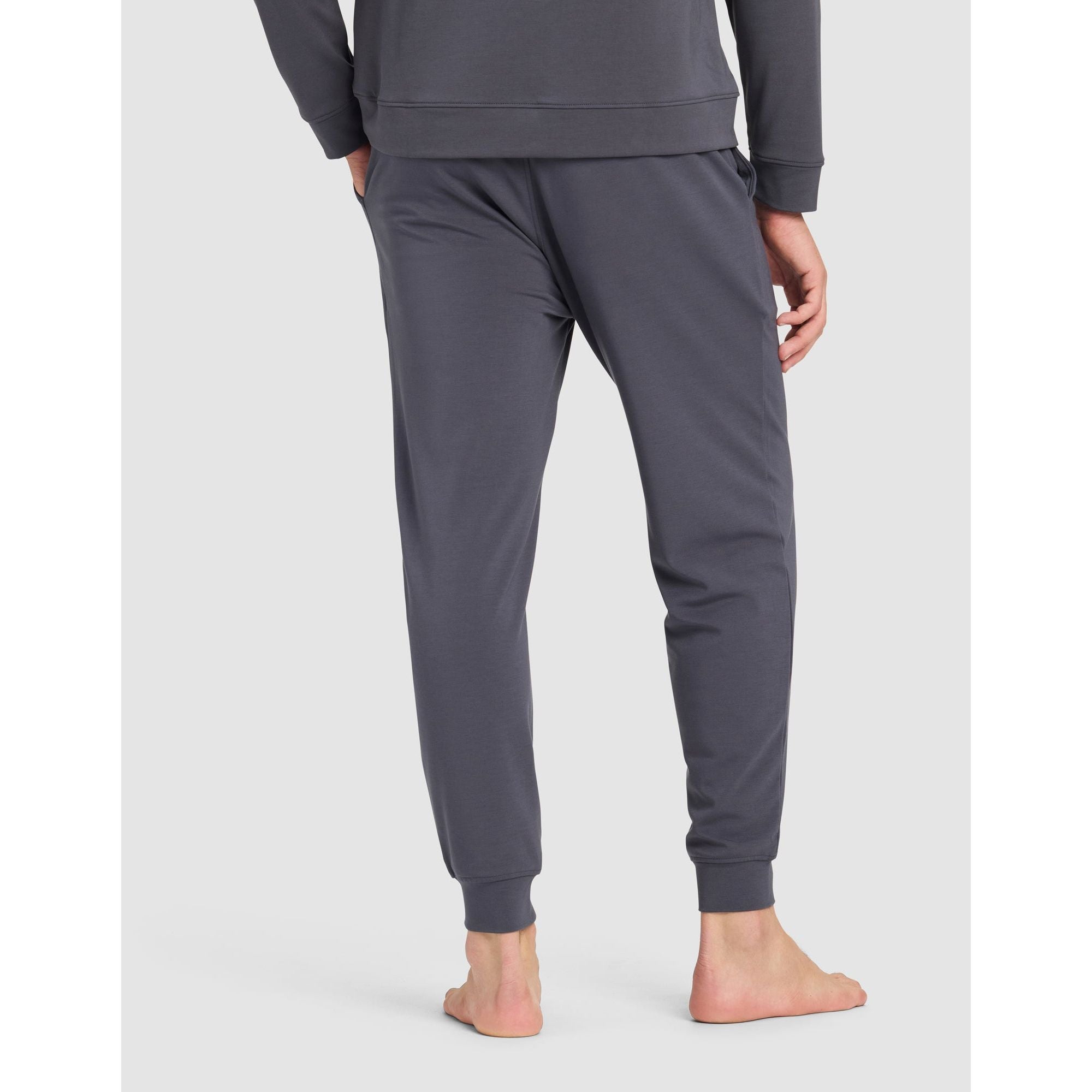 Person wearing a gray sweatshirt and pants on a white background
