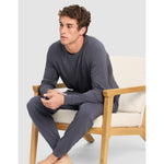 Man sitting on a chair wearing gray pajamas against a white background