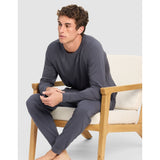 Man sitting on a chair wearing gray pajamas against a white background