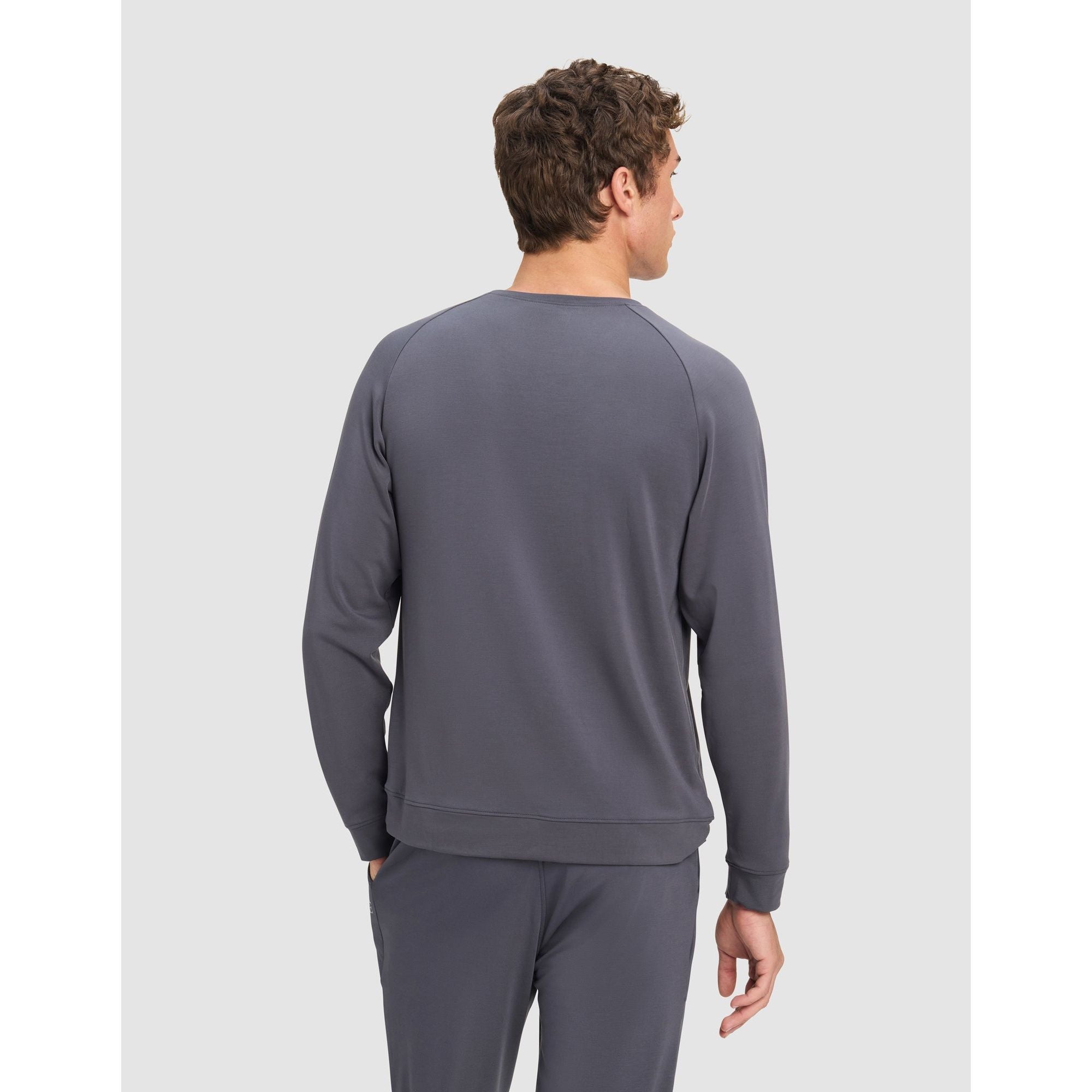 Man wearing a gray sweatshirt and pants on a light gray background