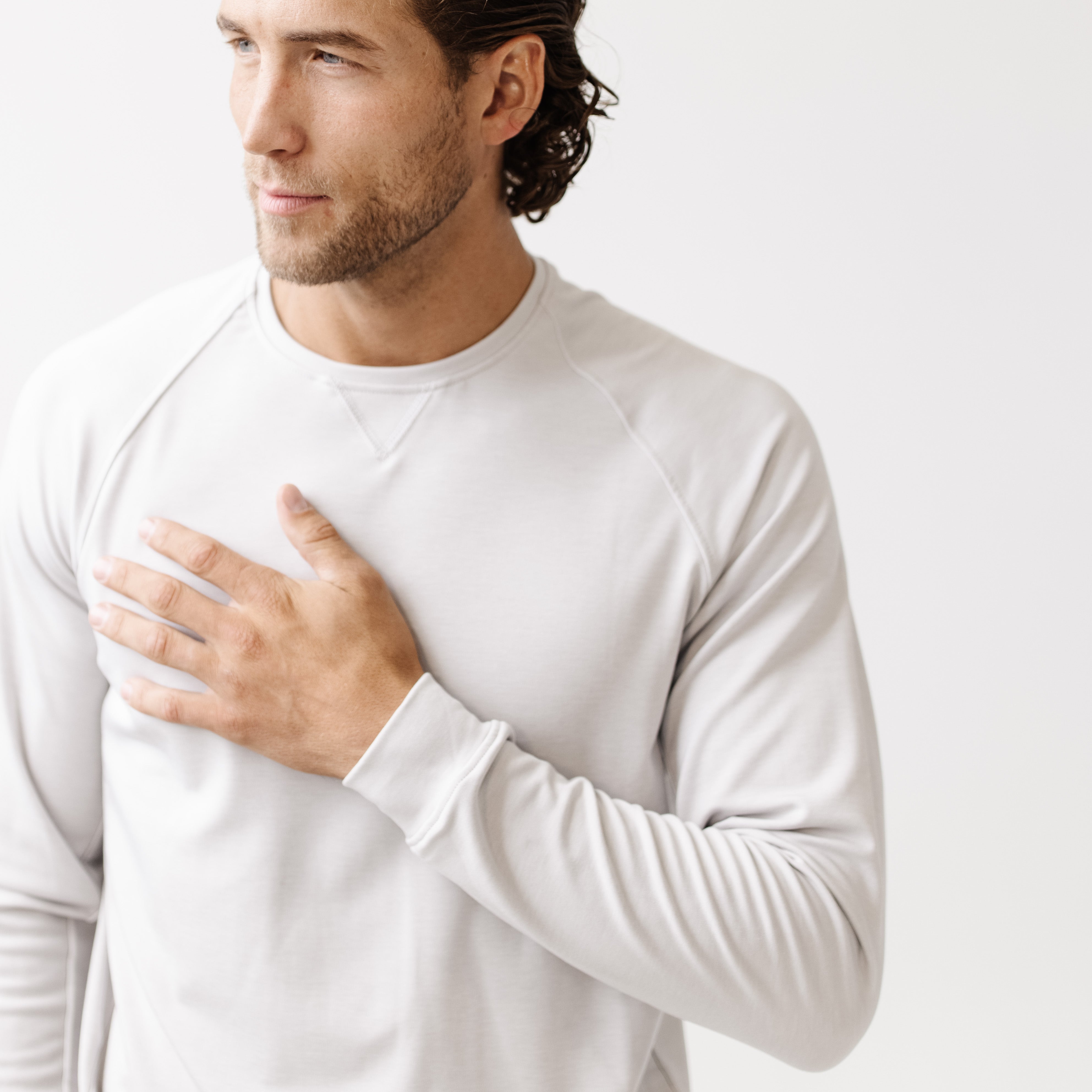 Man wearing a white long-sleeve shirt against a light background