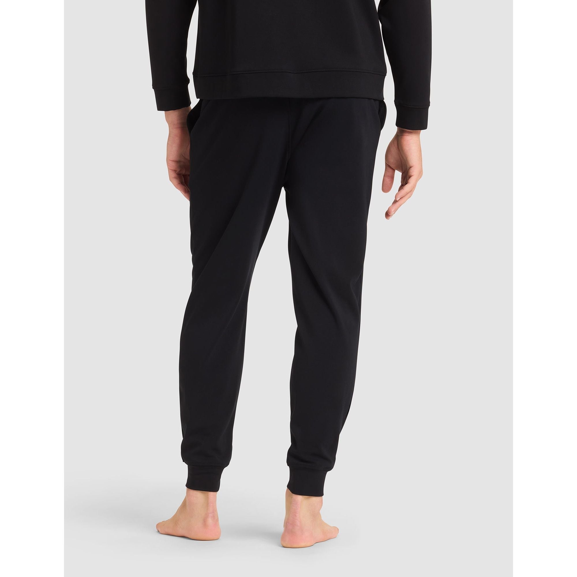 Person wearing black sweatpants on a light gray background
