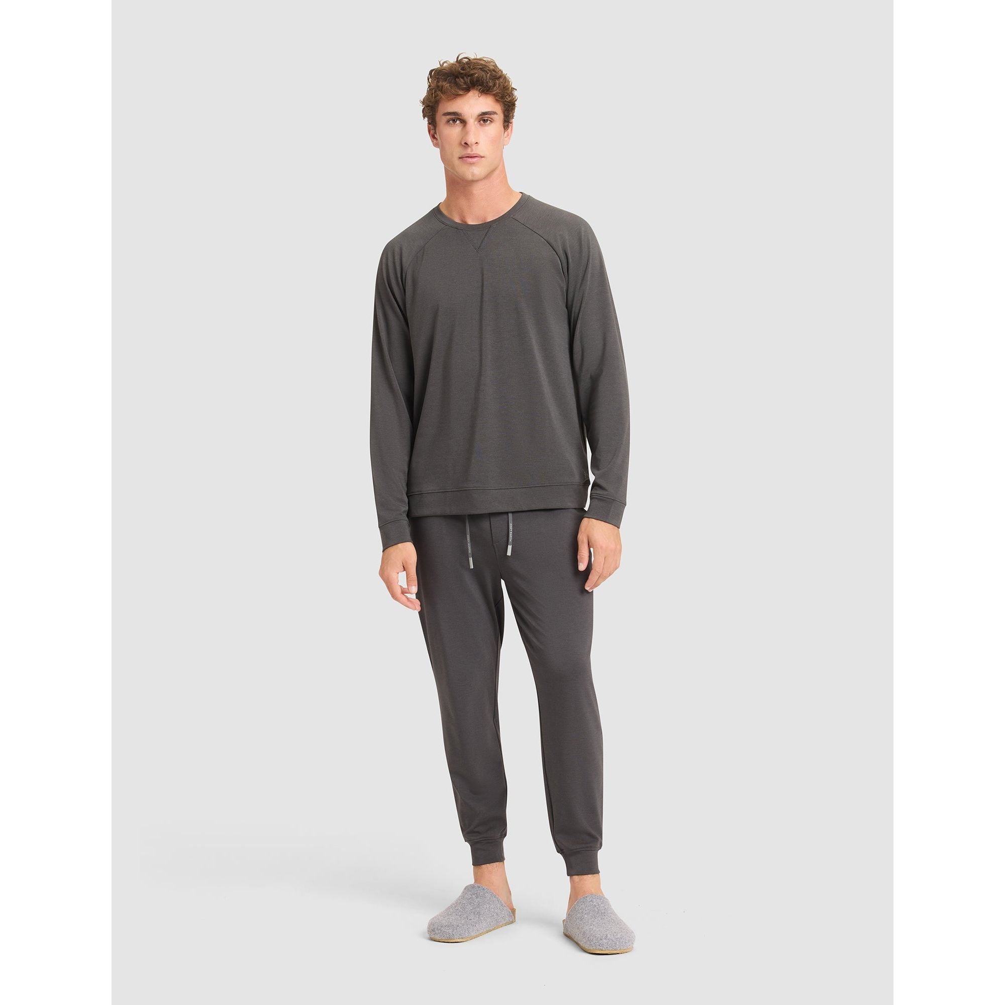 Man wearing a gray sweatshirt and pants set on a light gray background