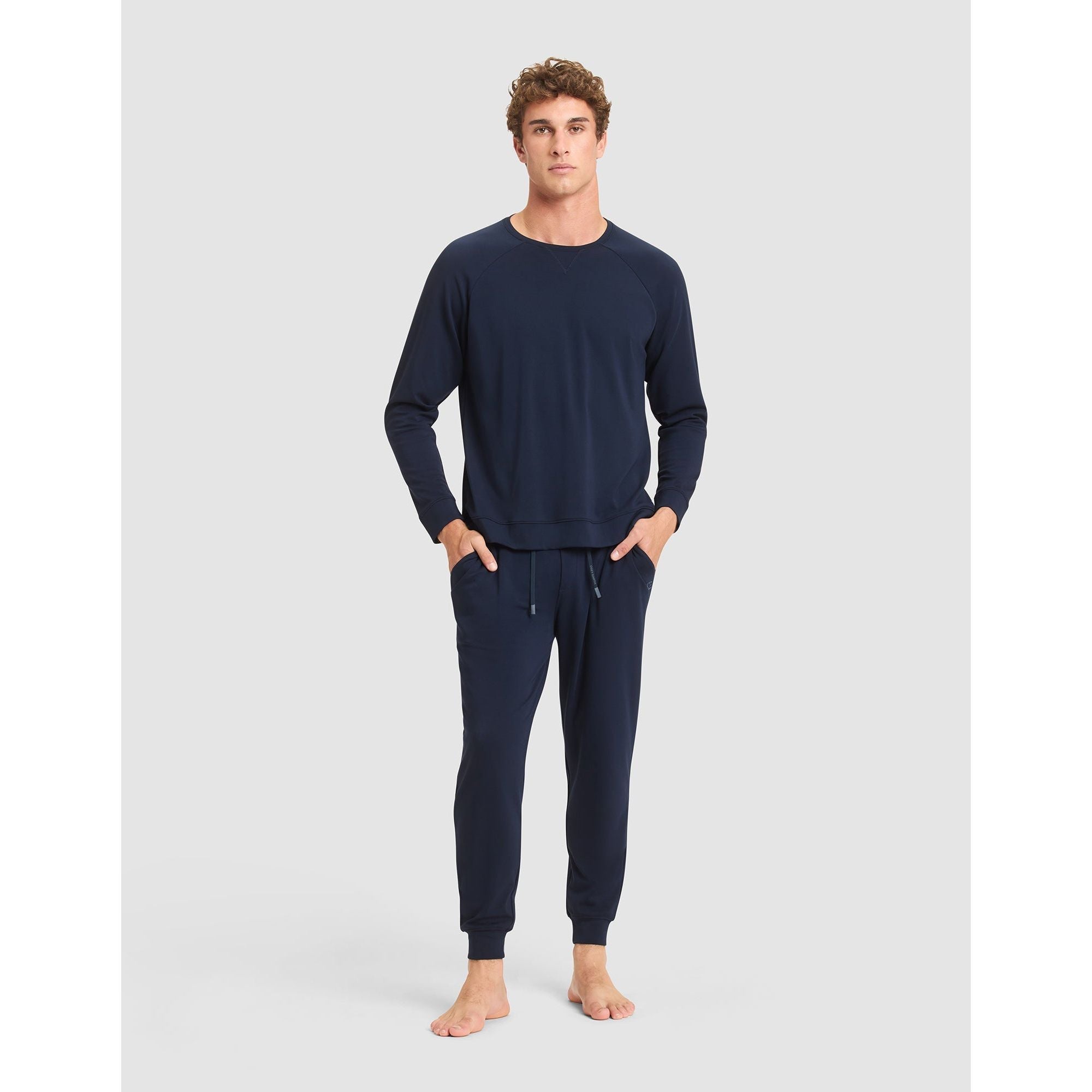 Man wearing navy blue pajama set on a light gray background