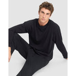 Man wearing a black long-sleeve top and pants on a white background