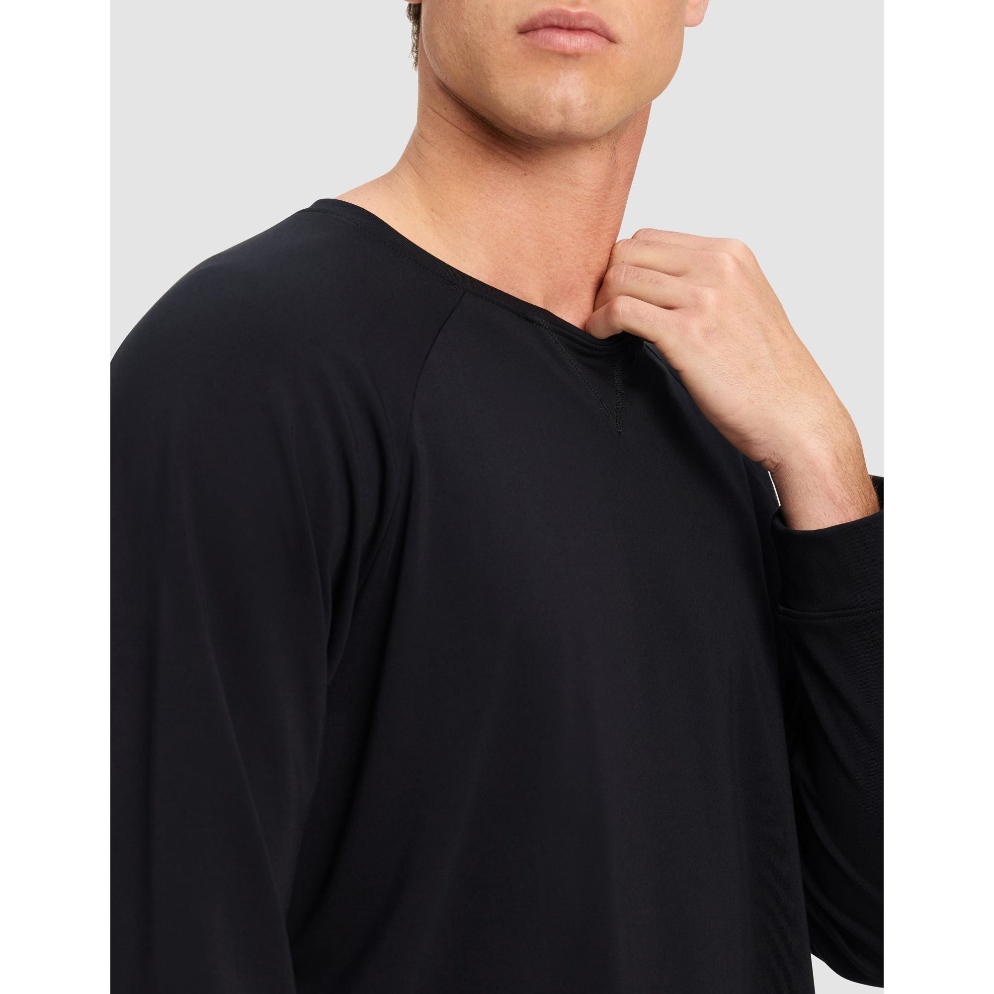 Man wearing a black long-sleeve shirt against a light gray background