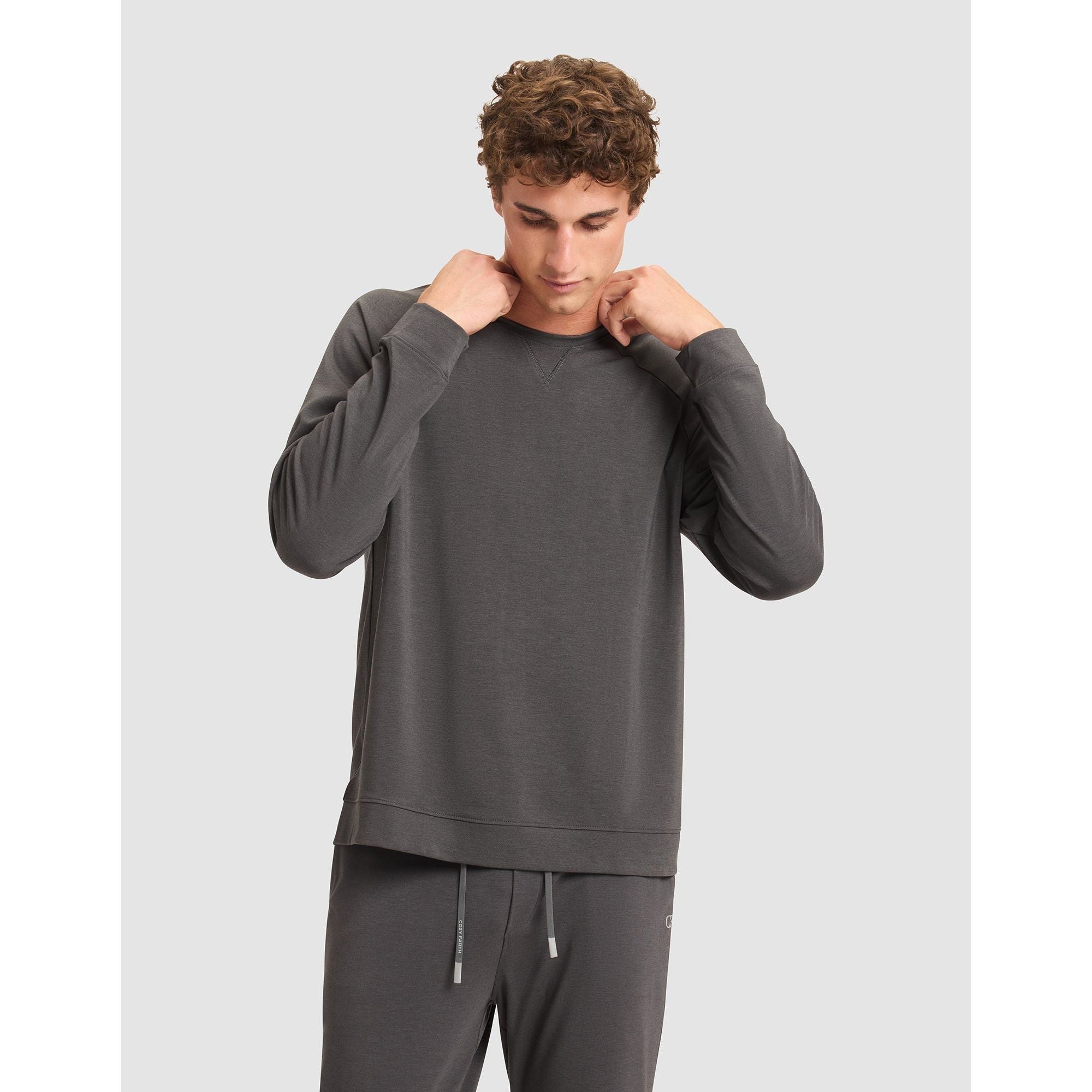 Man wearing a gray sweatshirt and pants on a light gray background