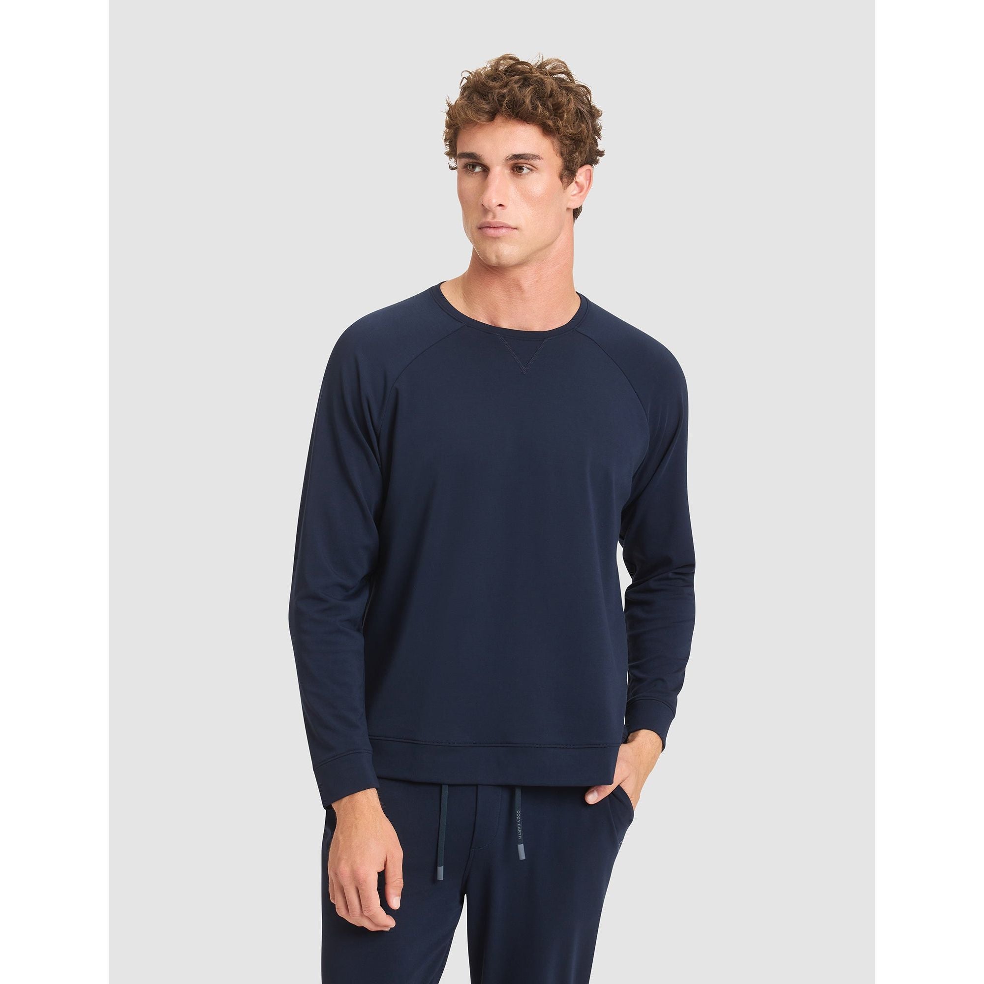 Man wearing a navy blue sweatshirt and pants on a light gray background