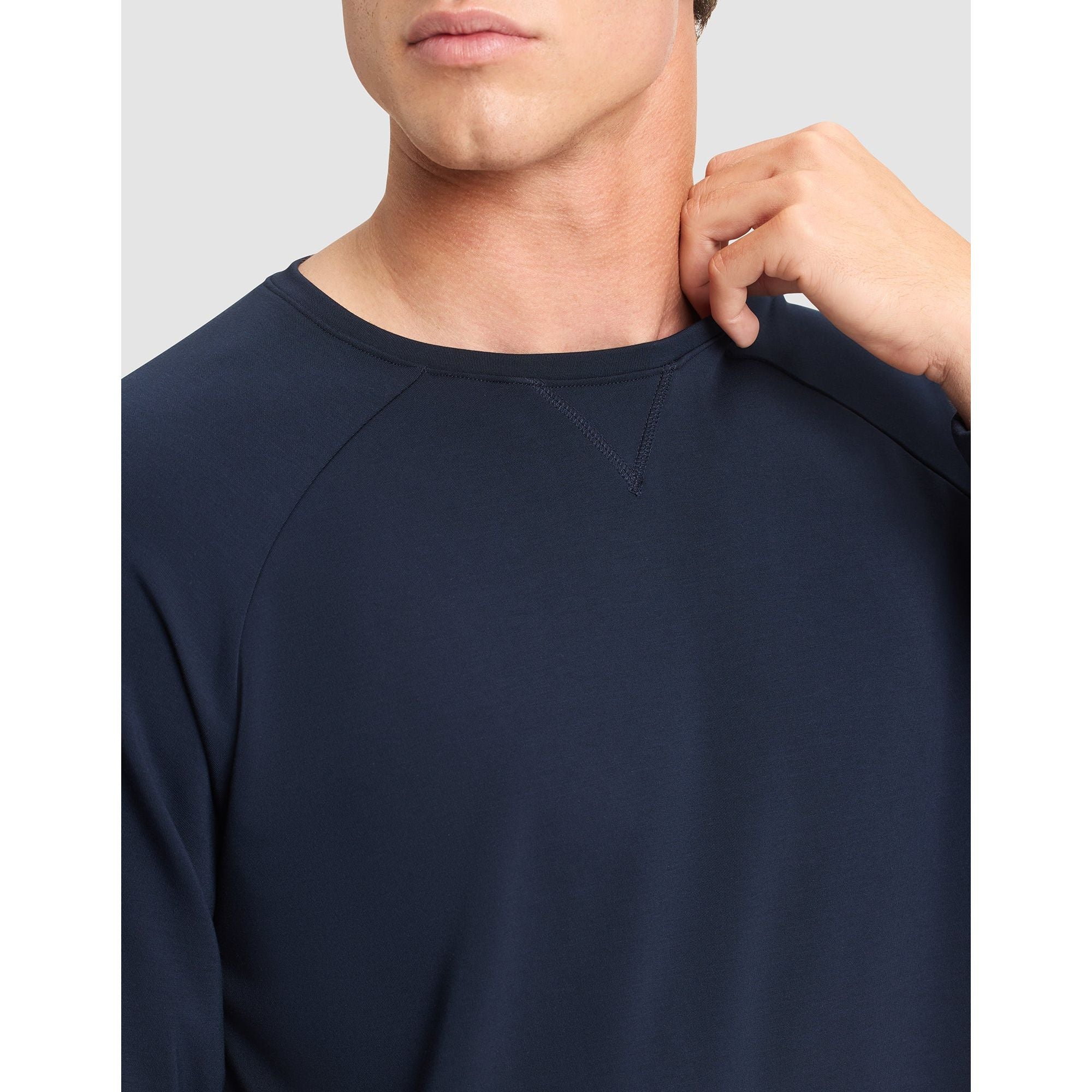 Navy blue long-sleeve shirt worn by a person on a light gray background