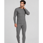 A man modeling a two-piece gray knit SilkCut Underwear thermal set consisting of a long-sleeve crewneck top and matching full-length pants, photographed against a solid light gray studio background.