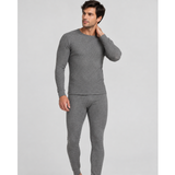 A man modeling a two-piece gray knit SilkCut Underwear thermal set consisting of a long-sleeve crewneck top and matching full-length pants, photographed against a solid light gray studio background.
