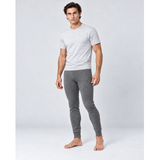 A man modeling a light gray short-sleeve t-shirt and dark gray heathered silkcut thermal leggings for men against a light gray studio background.