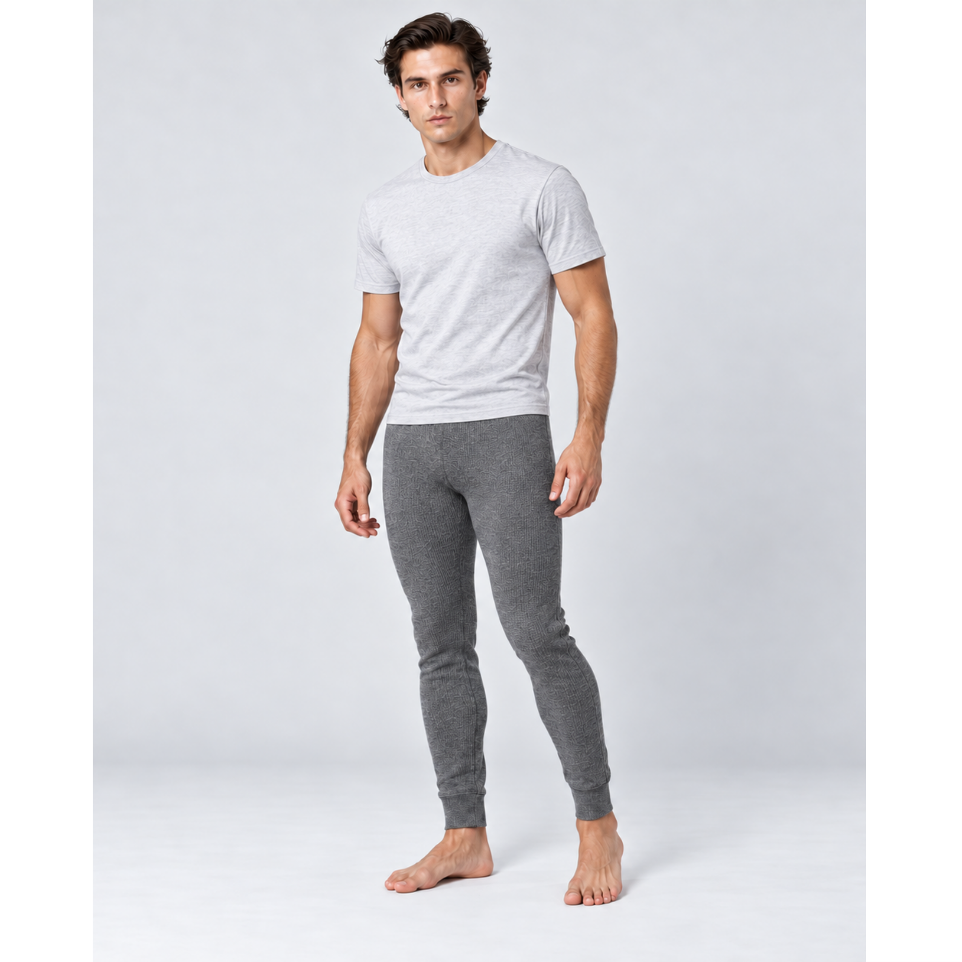 A man modeling a light gray short-sleeve t-shirt and dark gray heathered silkcut thermal leggings for men against a light gray studio background.