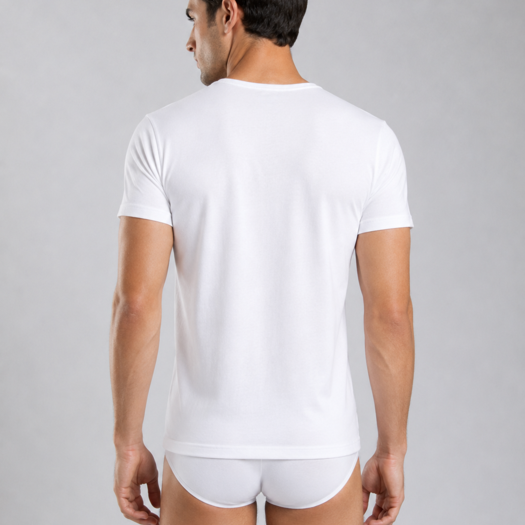 A man wearing a plain white micro modal air short-sleeve silkcut crew-neck t-shirt, and matching white briefs, photographed against a light gray studio background.