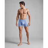 Man wearing light blue boxer briefs against a gray background